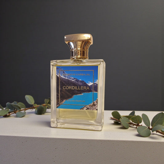 Frasco del Perfume Cordillera de Mauricio Carbajal  sobre una encimera clara y con un fondo tranquilo y hojas de eucalipto alrededor 