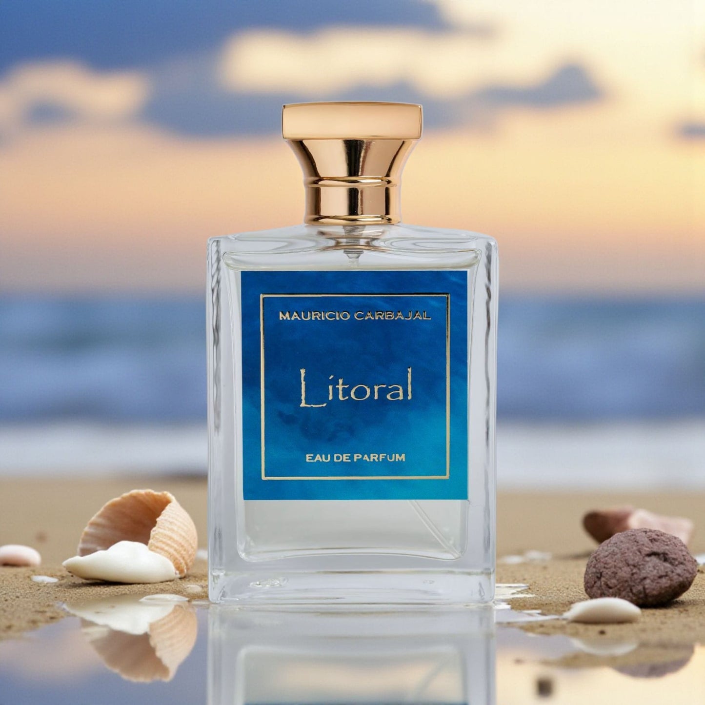 frasco del perfume Litoral de Mauricio Carbajal en la orilla con arena y conchitas marinas en el fondo el atardecer