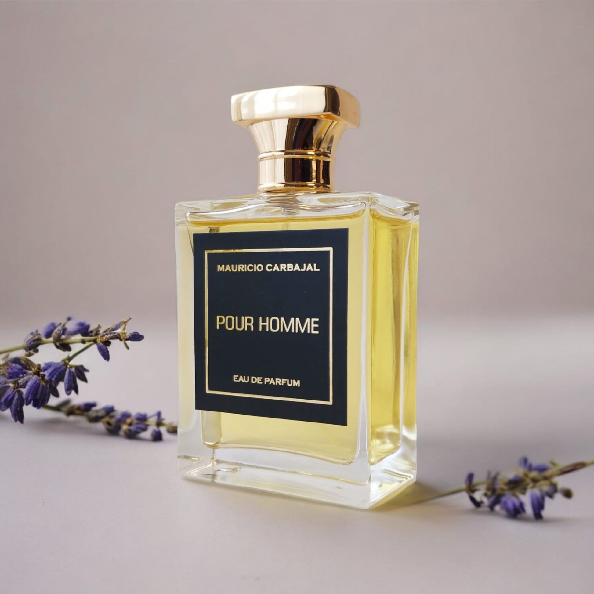 Frasco del perfume Pour Homme de Mauricio Carbajal con un fondo blanco y unas lavandas a cada lado mostrando la apertura del perfume.
